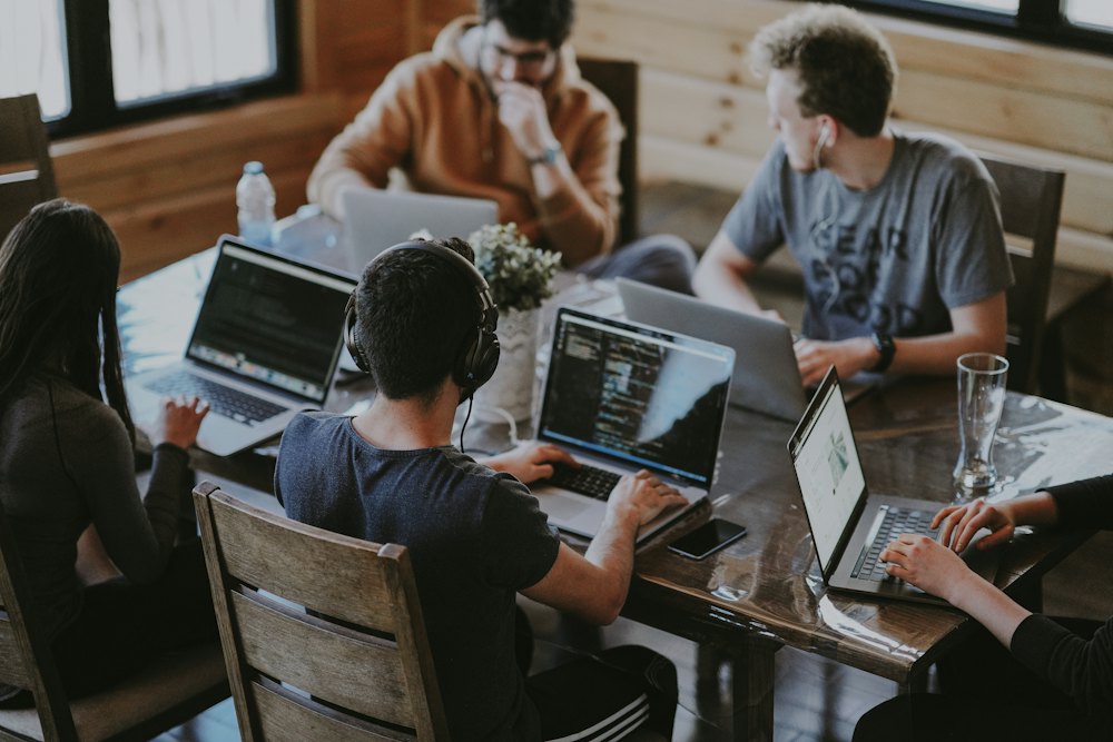 Equipe reunida em volta de uma mesa, trabalhando em notebooks